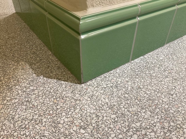 Eckdetail heller Terrazzo im Waschraum mit grünen Wänden