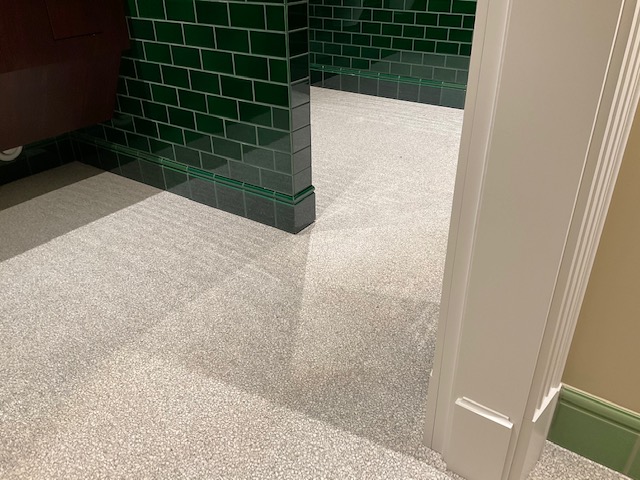 Bodendetail heller Terrazzo im Waschraum mit grünen Wänden
