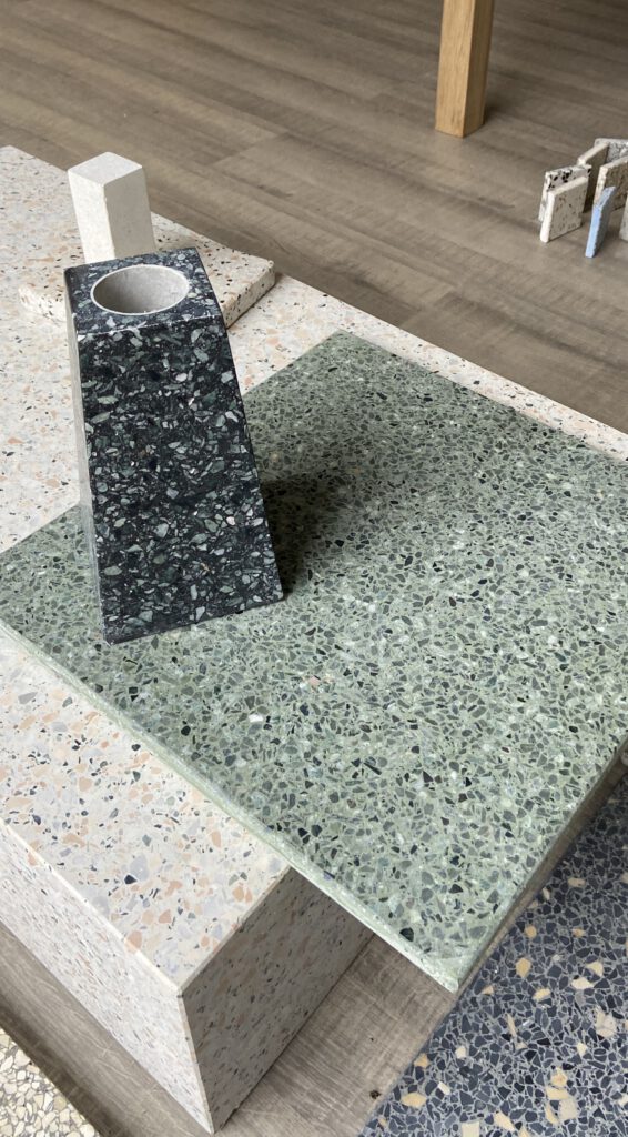 schwarze Vase aus Betonwerkstein auf grünem Terrazzo Muster